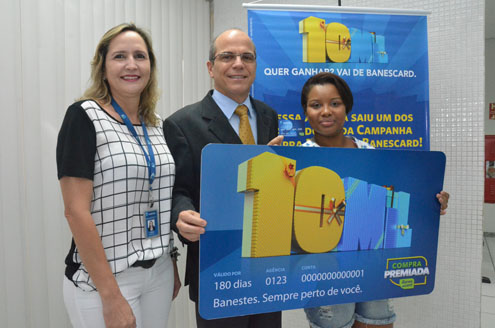 A auxiliar administrativa Natália Carvalho Martins recebe o cartão com limite de R$ 10 mil das mãos do presidente do banco, Guilherme Dias, e da gerente geral da unidade, Tânia Maria Borsoi.